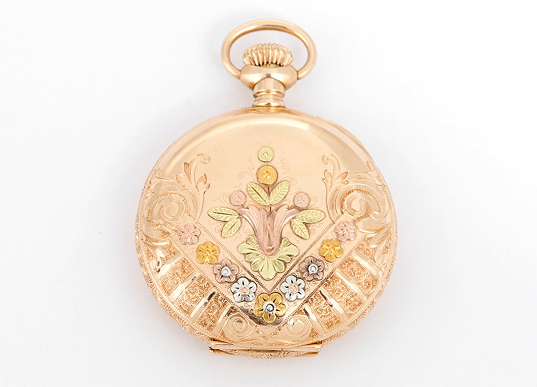 Manual winding; 7 jewel. 14k solid yellow gold O Size case with ornately engraved floral design in rose, yellow and white gold. White enamel dial with black Roman numerals; subseconds dial. Pre-owned ca. 1900. This watch would be beautiful worn on a