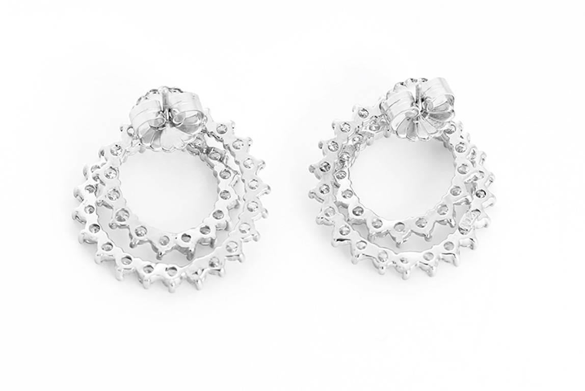 These stunning earrings feature a swirl diamond (6 carats) design in 18k white gold. Earrings measure apx. 1-inch in diameter. Total weight is 9.7 grams.