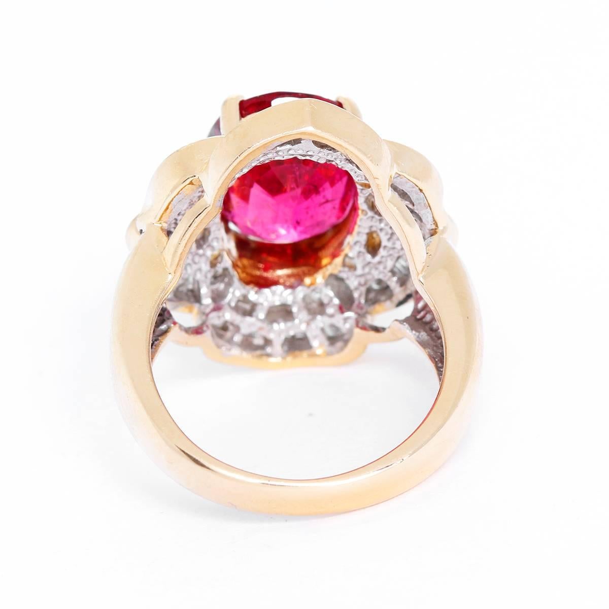 This stunning ring features central oval-cut rubellite tourmaline, with apx. 5.12 cts., surrounded by six round brilliant-cut and sixty-six baguette-cut diamonds, with apx. 0.79 cts. Total weight is 11.0 grams. Size 7.