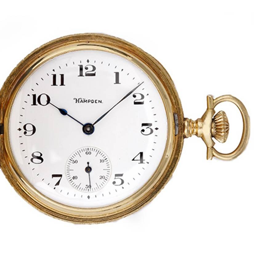 Hampden Yellow Gold Hunting Case Pocket Watch -  Manual winding. Solid  yellow gold case, beautifully engraved (45mm). Enamel dial with black Arabic numerals; seconds subdial at 6 o'clock. Pre-owned, ca. early 1900's.