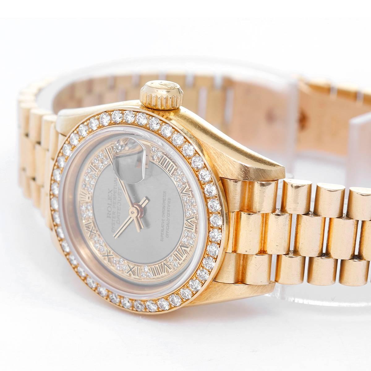 Rolex President Yellow Gold Diamond Bezel Ladies Watch -  Automatic. 18k Yellow Gold with Factory Diamond Bezel (26mm). Factory Gray Myriad Diamond Dial with Roman Numerals; Date at 3:00 o'clock. 18k Yellow Gold President hidden clasp bracelet.