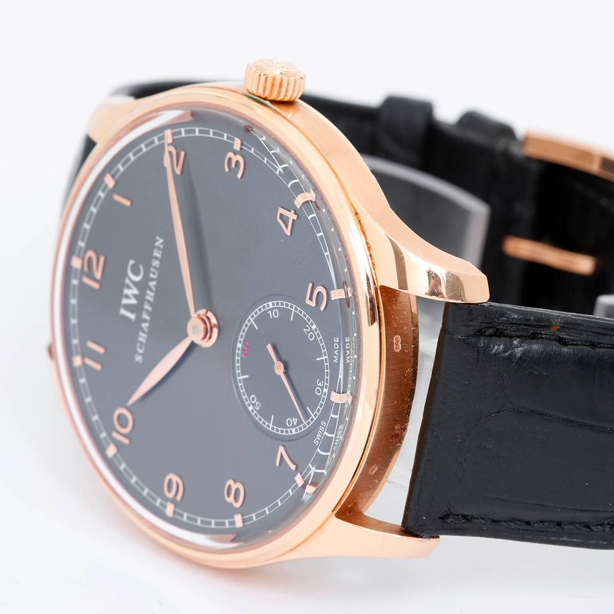 IWC Portuguese Rose Gold Hand Wound Men's Watch -  Manual Winding. 18K Rose Gold  ( 44 mm ). Black dial with Arabic numerals; sub dial at 6 o'clock. Black IWC leather strap.  Pre-owned with box and papers.