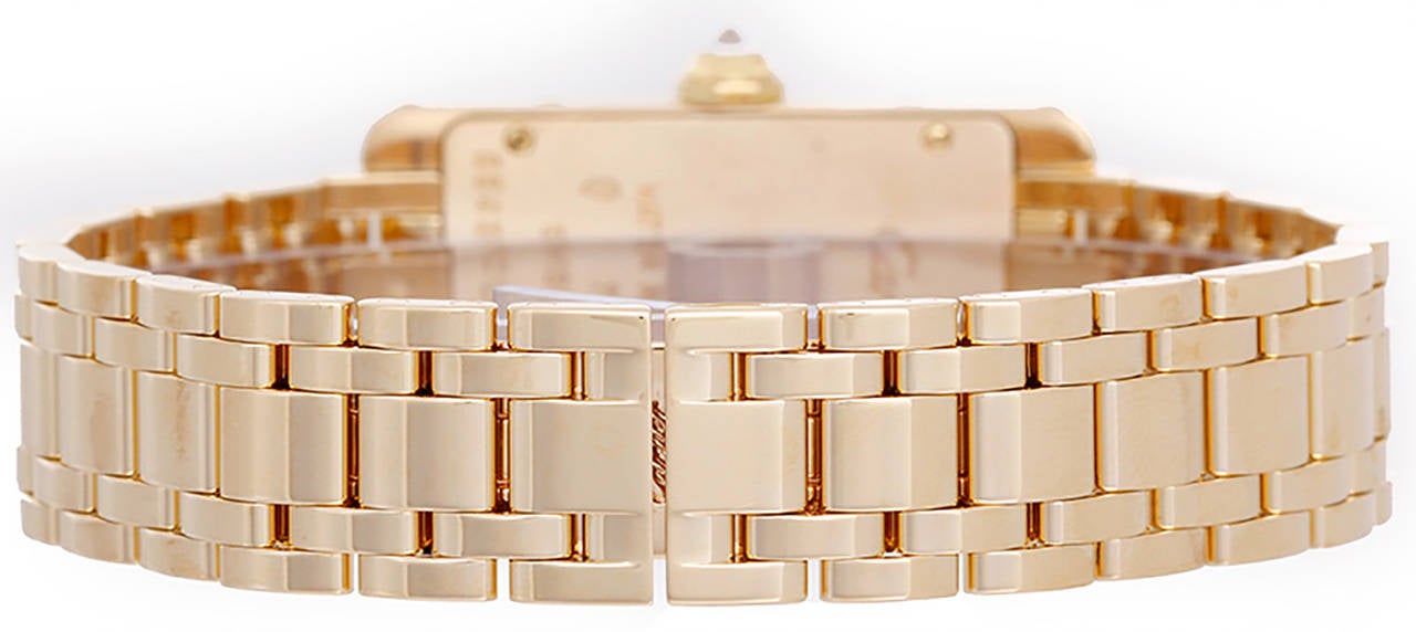 Quartz movement. 18k yellow gold case with 2-row factory diamond bezel (19mm x 40mm). Ivory colored with black Roman numerals. 18k yellow gold Cartier bracelet with deployant clasp. Pre-owned with box and books.