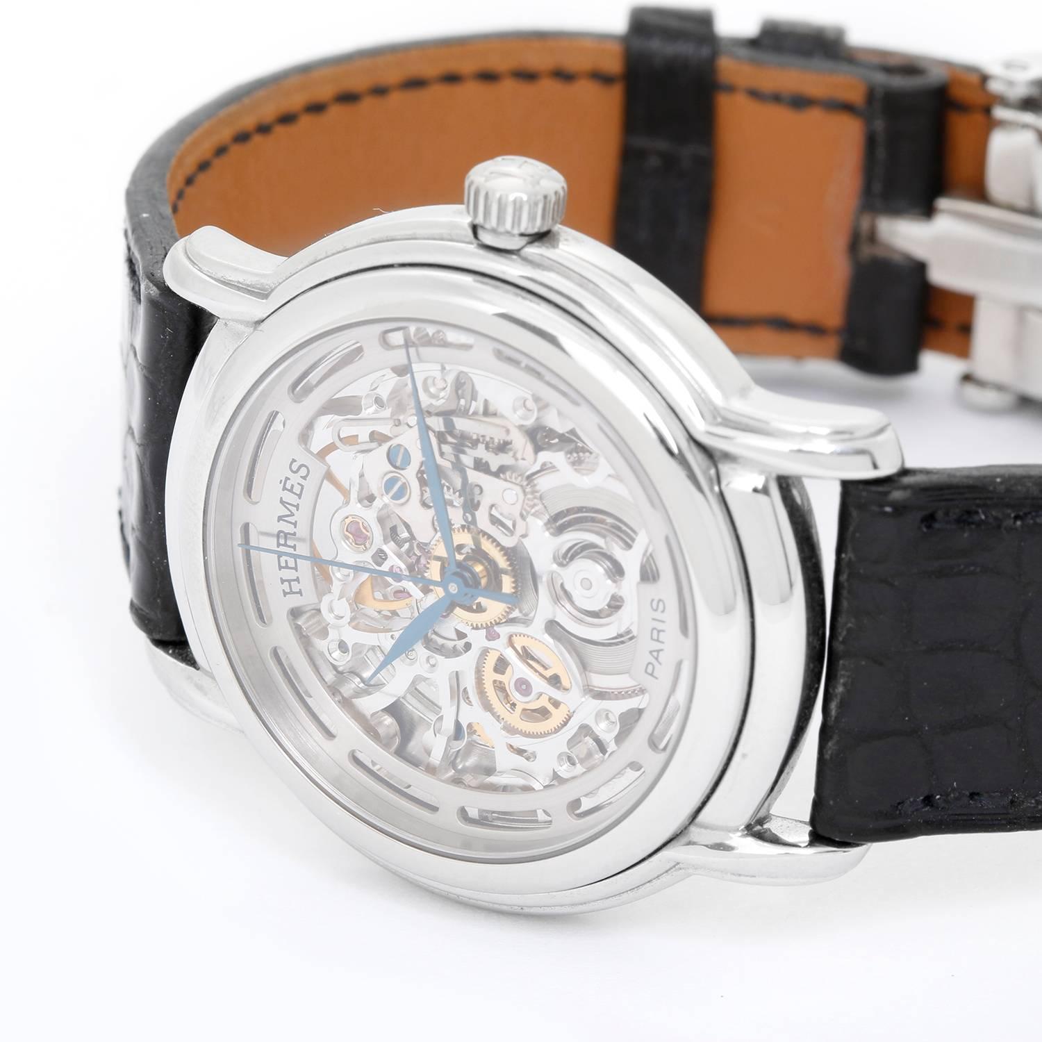 Hermes Stainless Steel Sesame TGM Skeleton Watch Ref. SM1.710 -  Automatic winding. Stainless steel case (36mm). Silver skeletonized dial with blue hands. Black strap band with stainless steel Hermes deployant buckle. Pre-owned with box and papers.