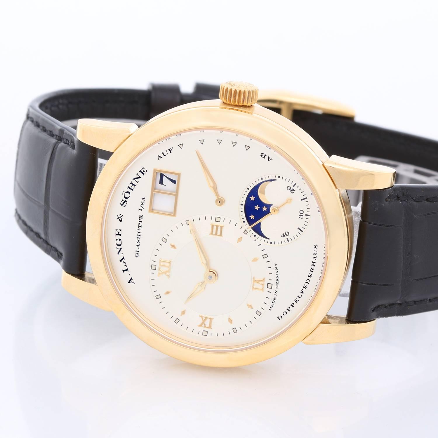 A. Lange & Sohne Lange 1 Moonphase Yellow Gold 109.021 -  Mechanical winding. 18K Yellow Gold  with a exposition back ( 38.5 mm ). Silver dial with gold hands; two sub dials with a large date. Black leather strap band with buckle. Pre-owned with A.