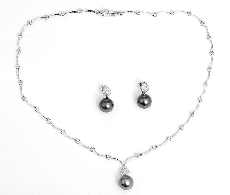 This stunning platinum scalloped necklace features diamonds at the lower part of the necklace. The necklace and earrings feature pave diamonds with a black pearl. This necklace is apx.16 inches in length. The total weight is 28.4 grams.