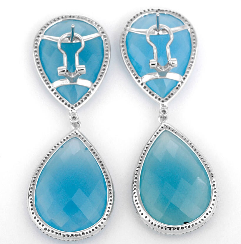 These amazing earrings are a show stopper. They feature 58.46 carats of faceted light blue agate stones surrounded by SI1 diamonds with a total diamond weight of 0.94 carats. The total weight of the earrings is 20.2 grams and they are 2-1/4 inch in