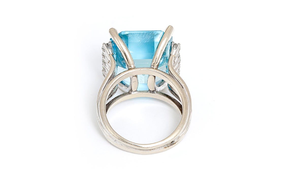 This amazing ring features a central emerald cut aquamarine, apx. 16.40 cts., accented by 10 round brilliant cut diamonds in 14k white gold. Stamped, 