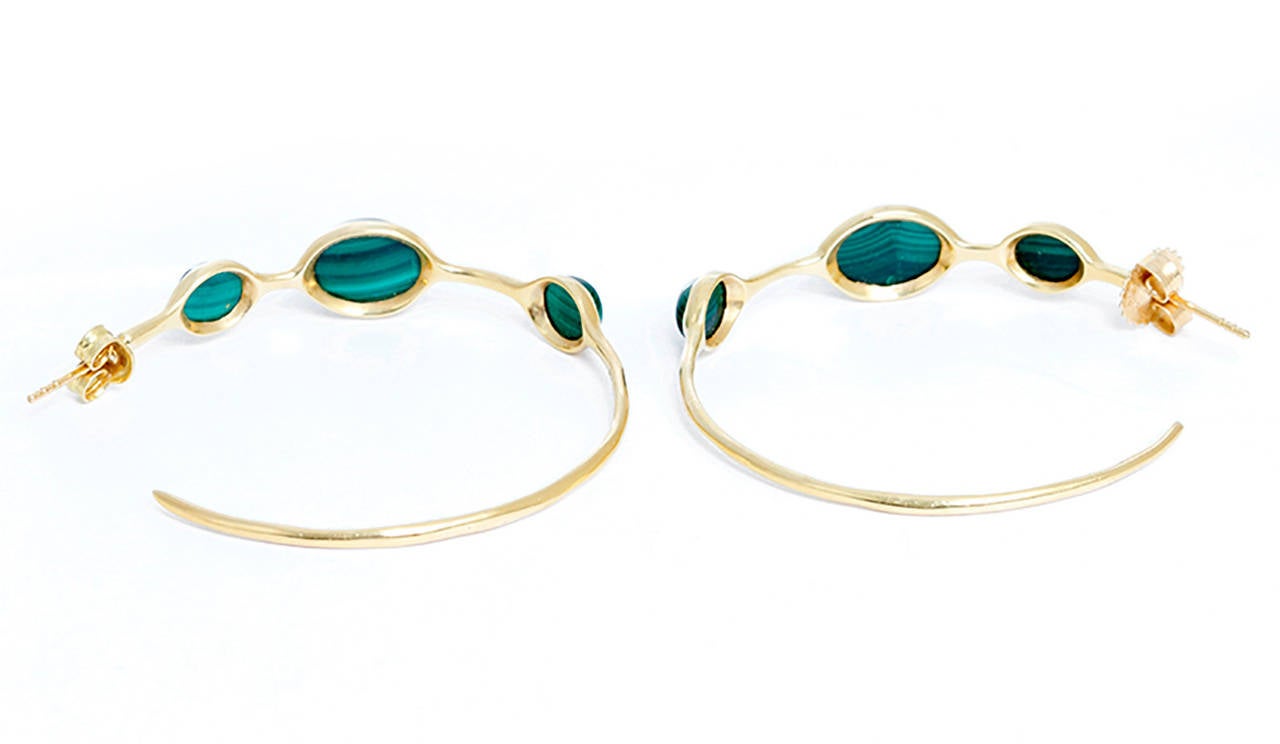 These amazing Ippolita hoop earrings  have bezel set malachite cabochon stations with clutch back closures in 18k yellow gold. Hoops measure apx. 1-1/2 inches in diameter. Total weight is 8.5 grams. These earrings can easily go from day to night!