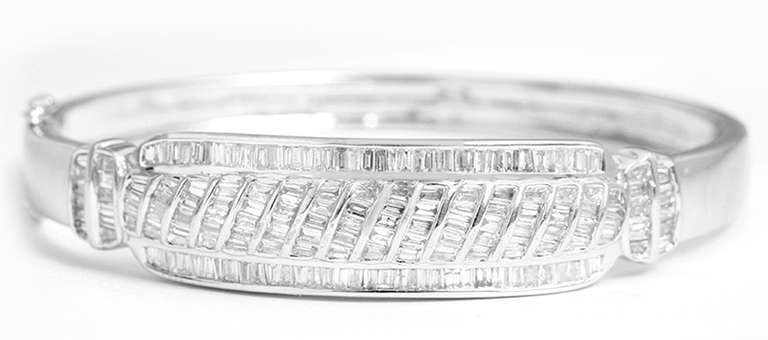 18k white gold slightly oval (apx. 2-1/4 in. x 2 in.) hanged bangle bracelet with safety clasp.  There are apx. 4 ct. of sparkling baguette diamonds.  The total weight of the bracelet is 27.89 grams.