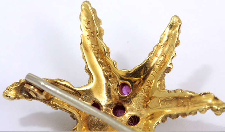 Starfish shaped 18k yellow gold brooch with 4 rubies.  It is about 1-inch x 1-inch in size. Stamped Tiffany & Co., Italy, K18. The weight is 4.2 grams..