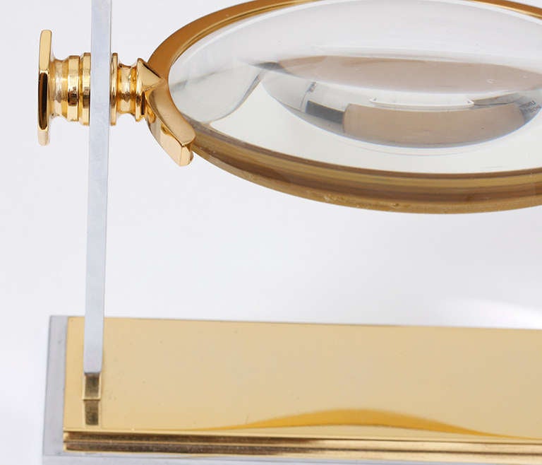 This elegant Karl Springer magnifying glass features chrome and brass. It is approximately 10.5 inches in height and approximately 9 inches in width.