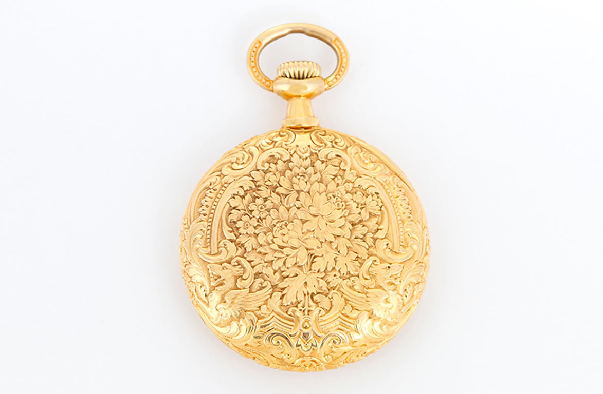 Manual winding. 18k yellow gold ornately engraved open face pendant/pocket watch (30mm diameter). Gold colored dial with guilloche center and black Arabic numerals. Pre-owned with custom box.