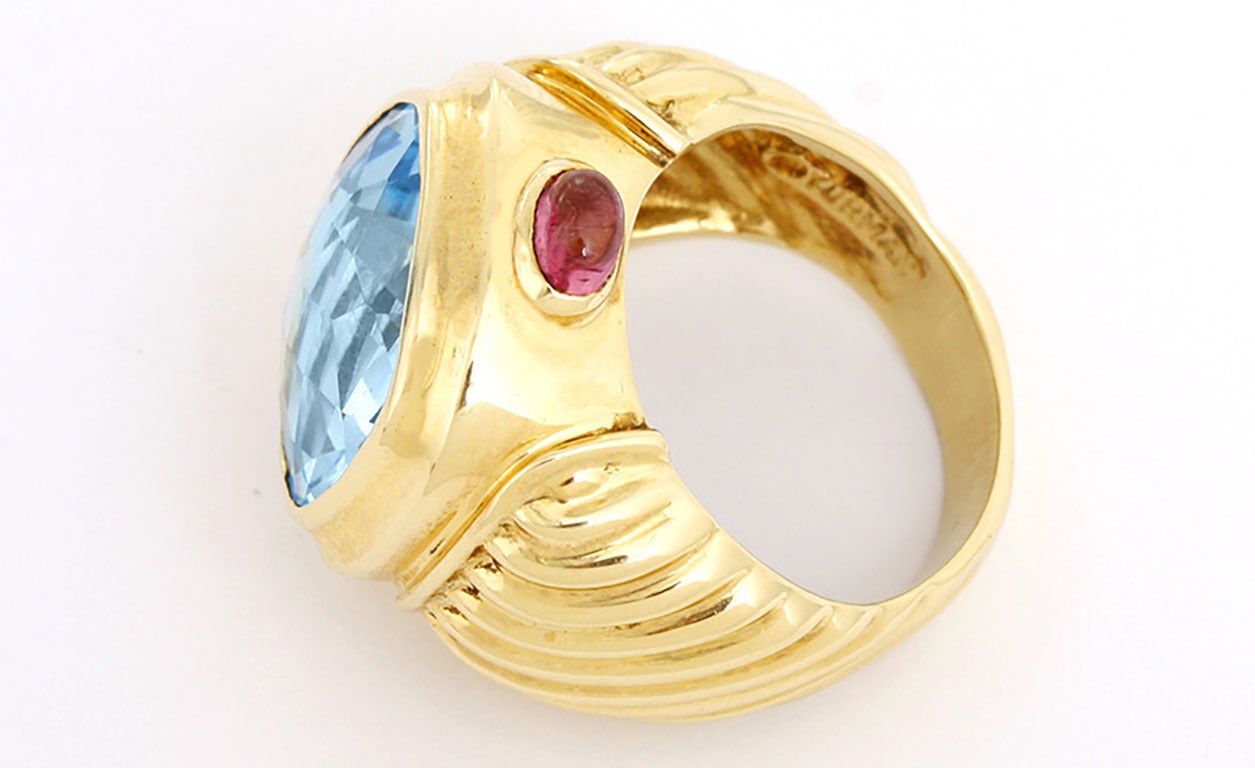 This ring features a topaz so bright and beautiful it is amazing. It measures 14mm x12mm.  This ring is no longer made and just a fabulous find. It features two small tourmalines on each side. It has a total weight of 16.1 grams and is a ring size