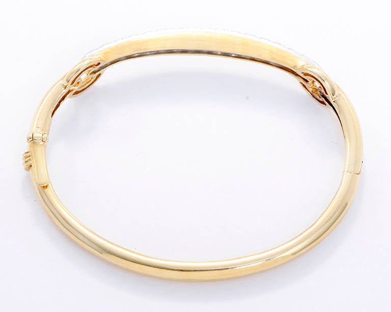 Beautiful oval shaped bangle. 18k yellow gold with 17 round brilliant cut diamonds set in platinum.  Apx. 1.70 ctw. Total weight of the bracelet is 18.6 grams.  The hinged bracelet has a slide closure with foldover safety clasp. The inside of the