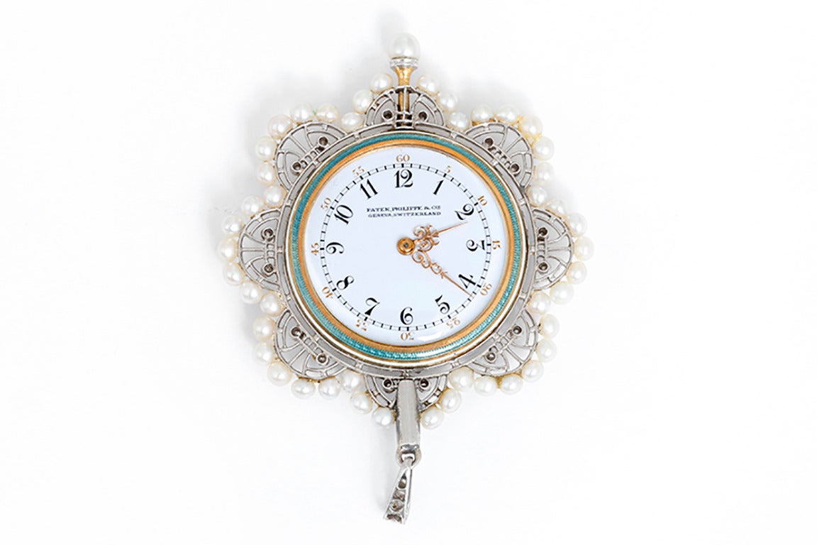 Manual-wind movement. White and yellow gold case with scalloped filigree edge adorned with 47 small pearls and 2 diamonds in each scallop on the back. The case back is a beautiful powder blue guilloche enamel with diamonds. White enamel dial with