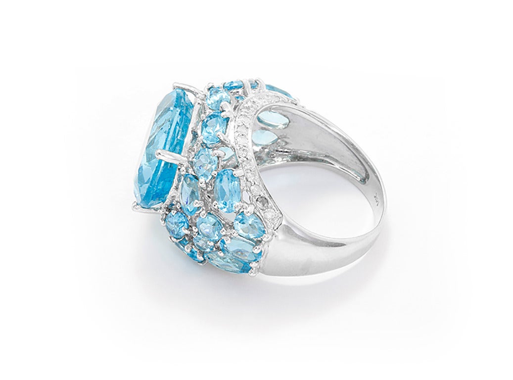 This stunning 14k white gold ring features blue topaz, round-cut diamonds and 25 round, oval, marquise and pear-cut blue topaz set around a larger oval-cut blue topaz weighing approximately 11.07 cts. Ring size: 7-1/2. Total weight is 9.3 grams.