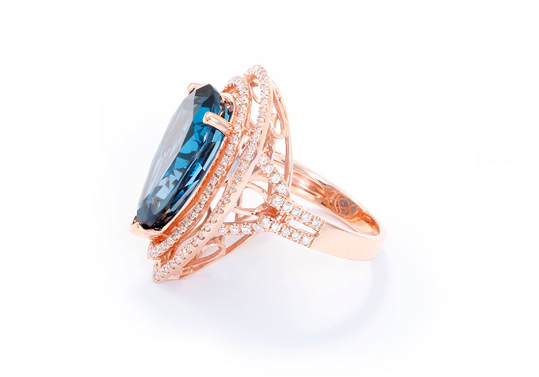 Cette bague étonnante présente une grande topaze bleue foncée, taillée en poire (13,38 cts)  avec une double bordure de diamants (0,89 ct.). L'anneau mesure environ 1-1/16 pouces de longueur et environ 13/16 pouces dans sa plus grande largeur. La