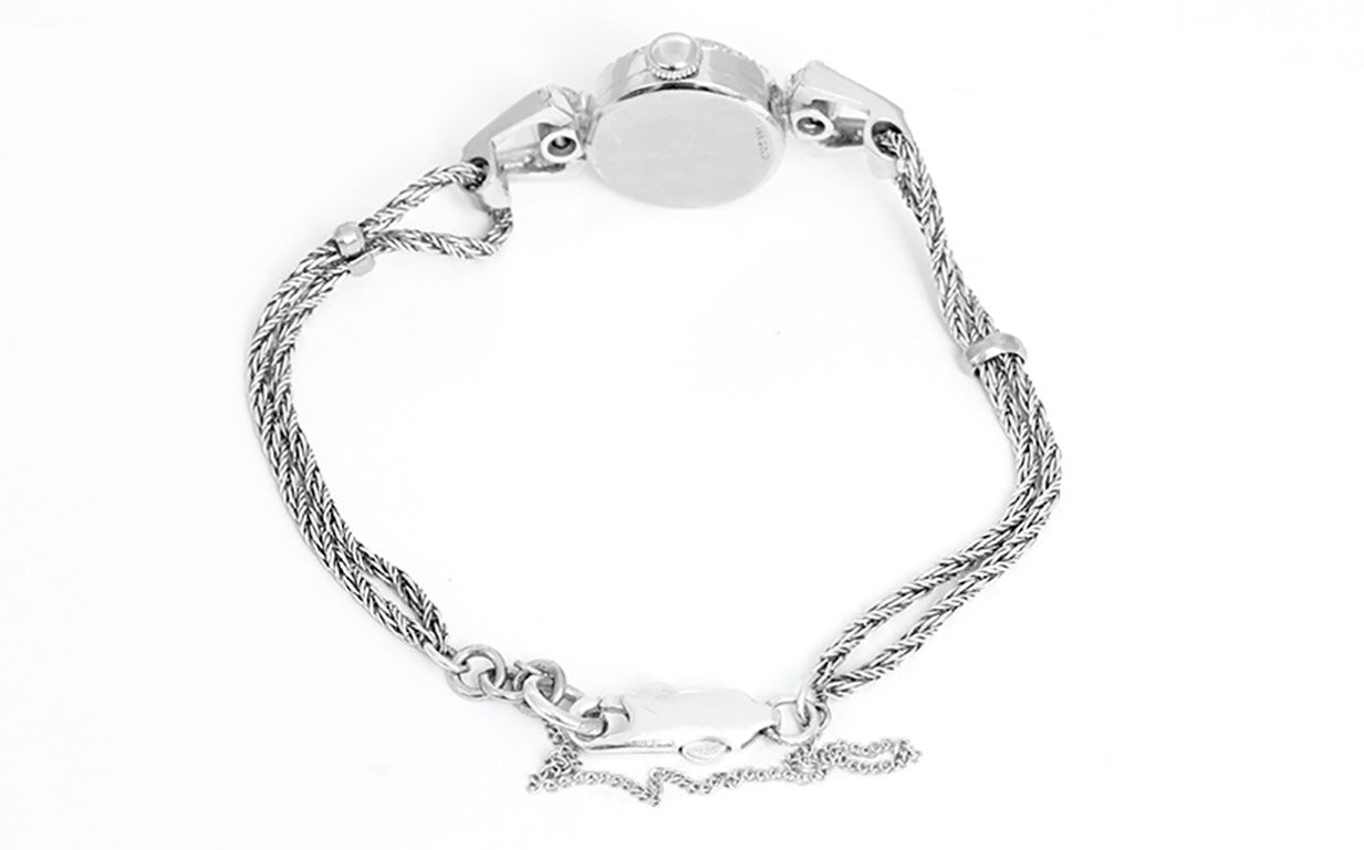 Manual-winding Swiss movement. 14k white gold case with diamond bezel and lugs, 15mm diameter. Silvered dial. 14k white gold double rope bracelet with safety chain will fit apx. 6-3/4-inch wrist.