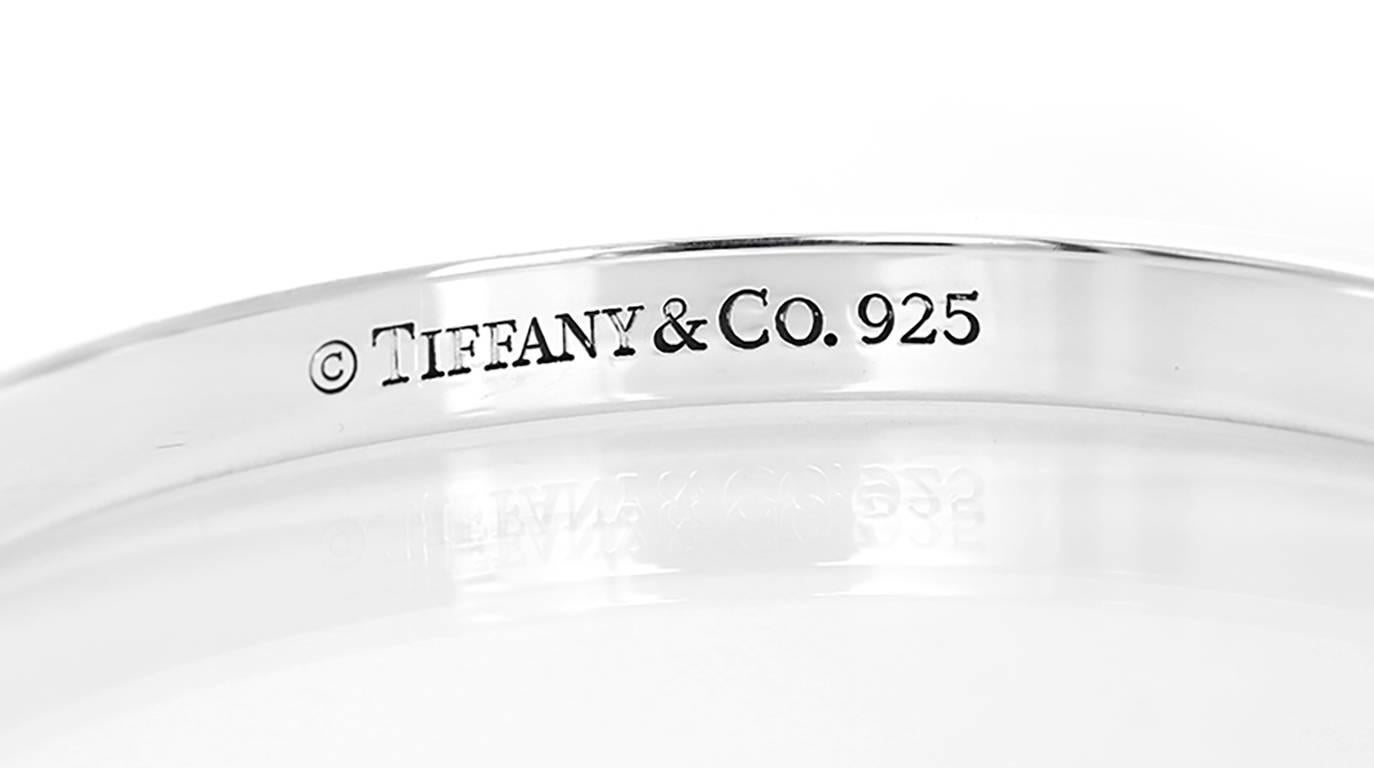 This Tiffany & Co. Notes bangle features elegant script, inspired by handwritten invitations in sterling silver. Bangle measures apx. 1/4-inch in width and fits up to a 7-inch wrist. Stamped 