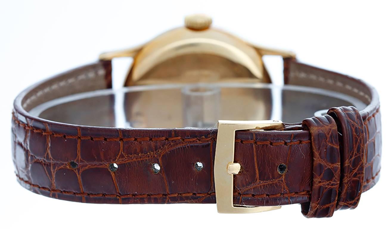 Manual winding. 18k yellow gold case (31mm diameter). Black dial with gold stick markers. Strap band with 18k yellow gold Patek Philippe buckle. Pre-owned.