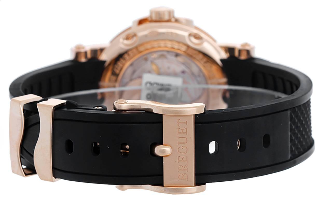 Automatic winding. 18 rose gold case with exposition back  (39mm diameter). 2-tone silvered dial with brown guilloche center and outer ring. Gold Roman numerals; big date at 6 o'clock position. Rubber strap band with 18k rose gold Breguet deployant