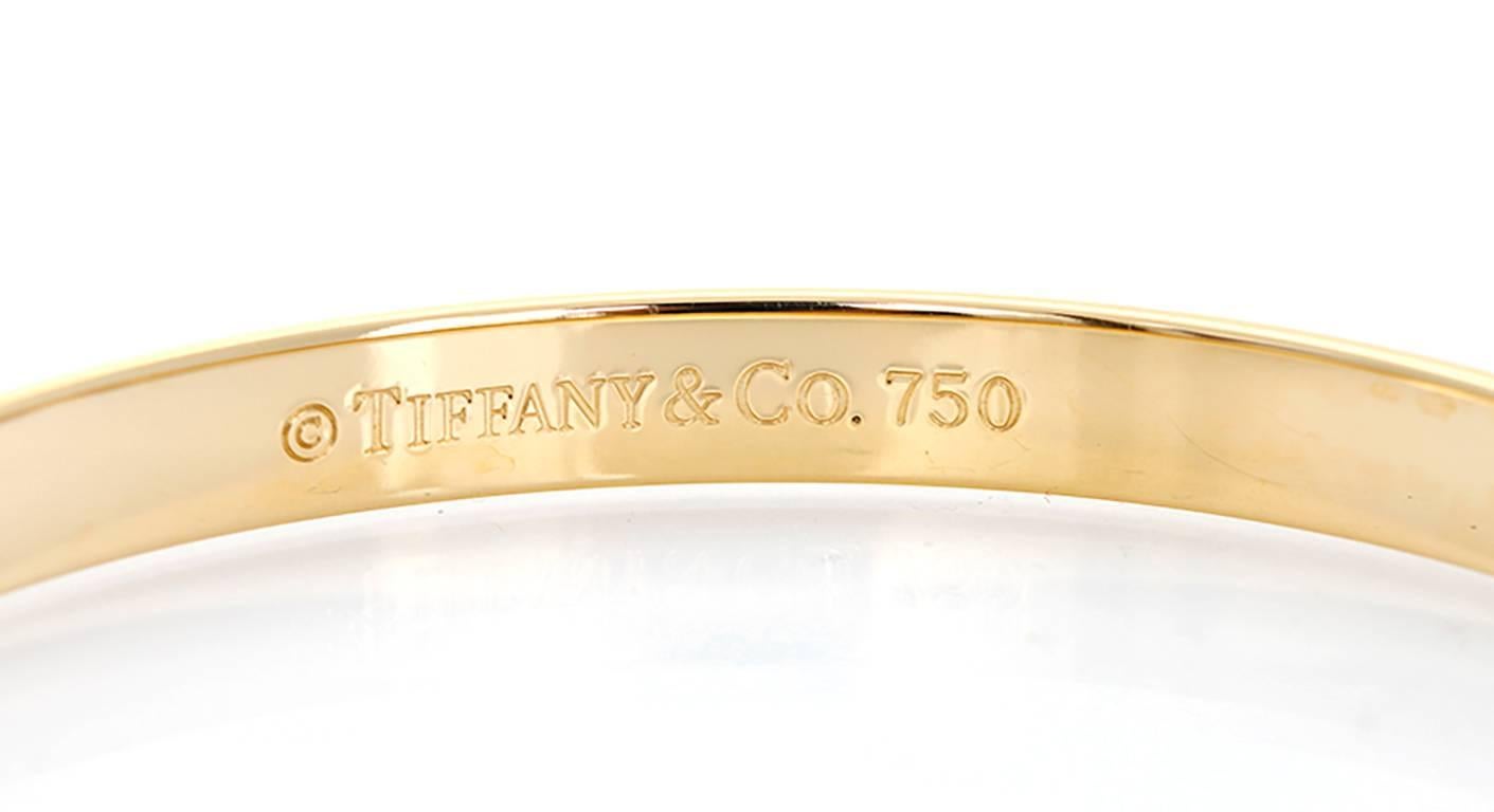 This Tiffany & Co. Notes bangle features elegant script, inspired by handwritten invitations in 18k yellow gold. Bangle measures apx. 1/4-inch in width and fits up to a 7-inch wrist. Stamped 