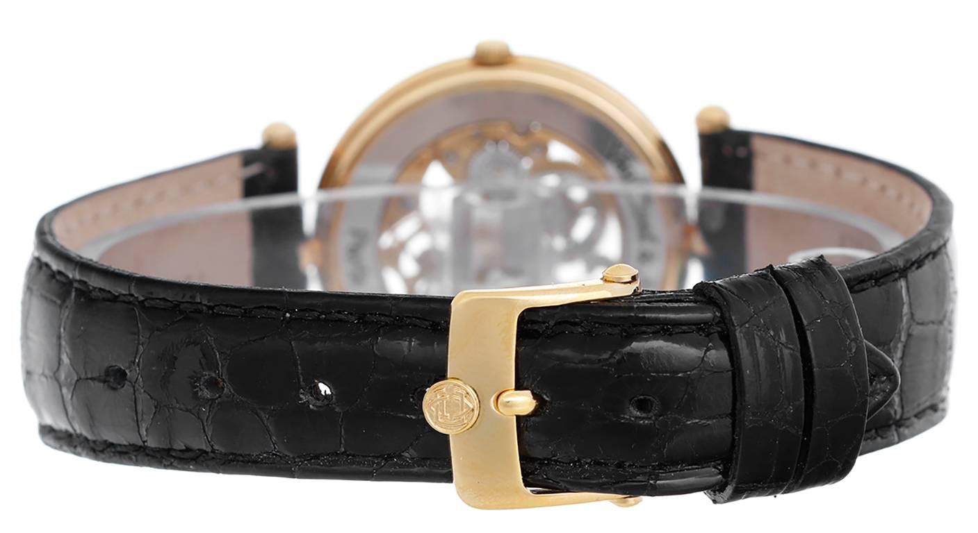 Manual winding. 18k yellow gold case with exposition back  (32mm diameter). Skeletonized dial to view movement with 2-rows of diamonds around outer edge. Black patent croc strap band. Pre-owned with custom box.