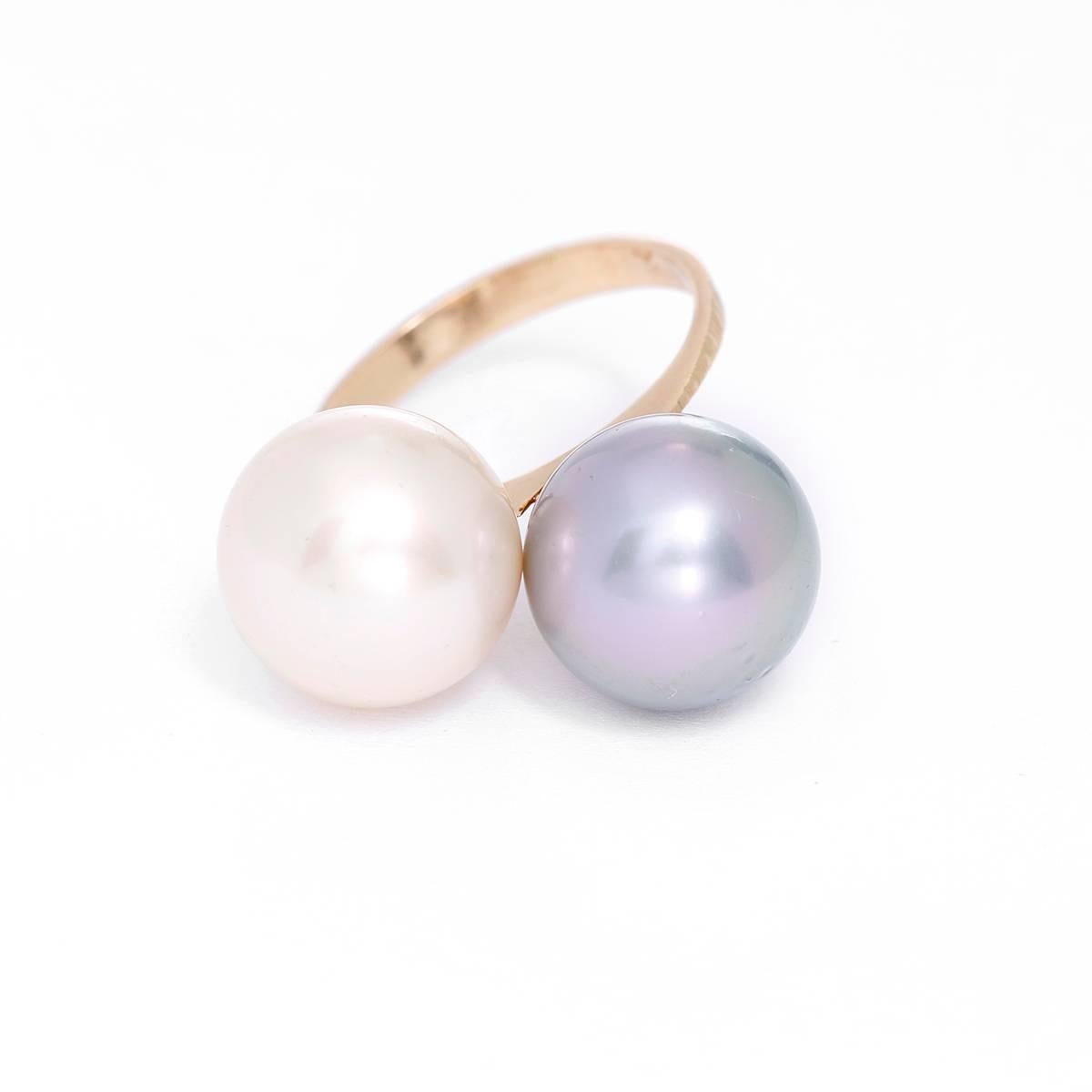 This beautiful ring features one white pearl and one gray pearl apx. 10 mm each. This ring is a stunning statement and is apx. a size 7 and can be sized.