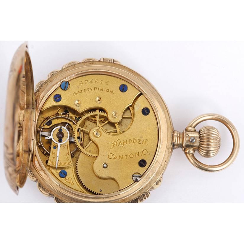 Hampden 14k Yellow Gold Scalloped Case Manual Winding Pocket Watch.  Elaborately engraved yellow gold scalloped case. White enamel dial with black Roman numerals. Pre-owned, ca. early 1900's.