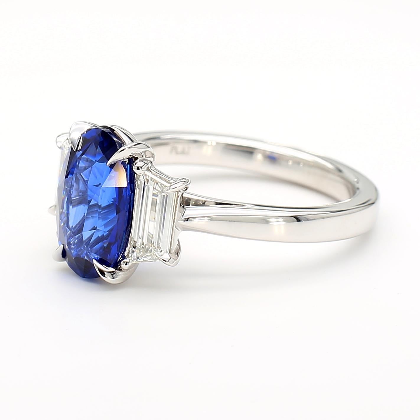 Il bellissimo anello con zaffiro di RareGemworld. Montato in una splendida montatura in platino con uno zaffiro blu naturale dal taglio ovale. Lo zaffiro è circondato da due diamanti bianchi naturali a taglio trapezoidale. Questo anello è destinato