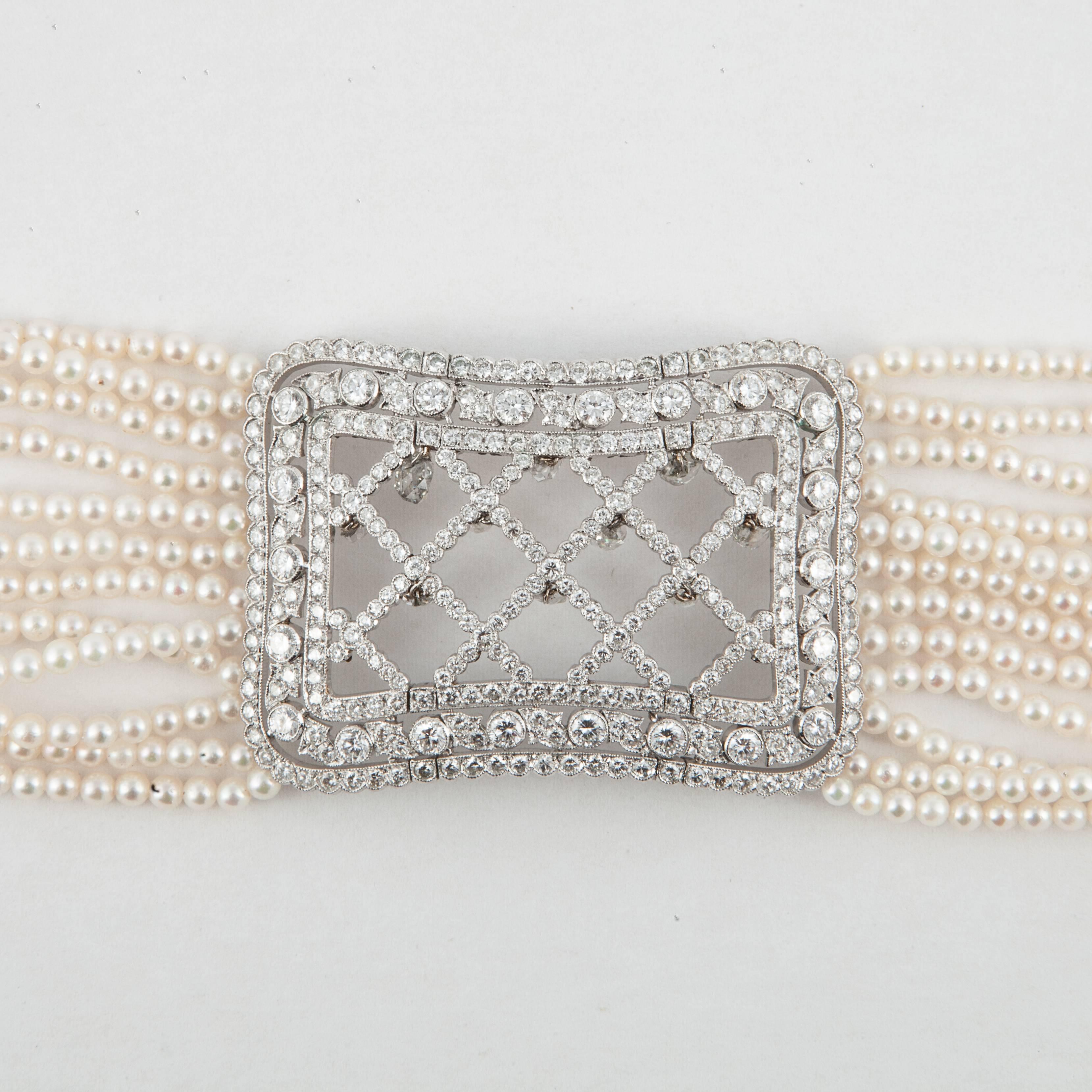 Collar necklace consists of twelve strands of small seed pearls with a diamond plaque in the center.  There are ten briolette diamonds dangling from the central plaque and a total of 409 round brilliant-cut diamonds, totaling 16.50 carats, G-I color