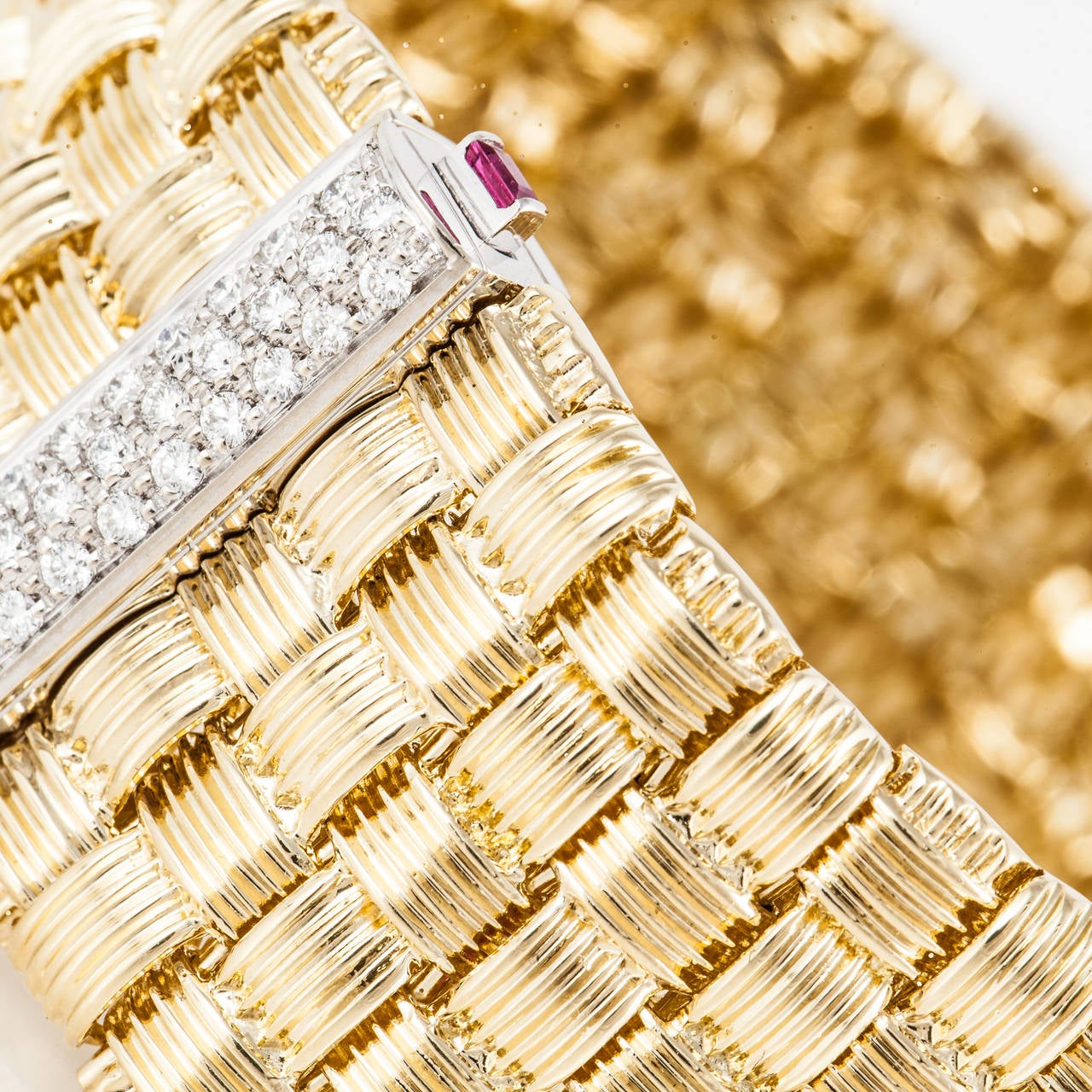 Woven 18K yellow gold bracelet by Roberto Coin.  Features a slide clutch clasp with diamonds and rubies.  There are thirty one (31) round diamonds totaling .60 carats.  They are G-H in color and VS2 in clarity.  There are also two (2) square cut