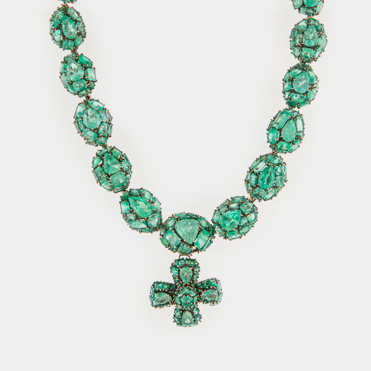 Versatile jewelry suite by Marilyn Cooperman that includes a necklace, earrings and removable pendant that may also be worn as a brooch.  The necklace features domes of different sized and shaped emeralds with a detachable Maltese cross pendant/pin.