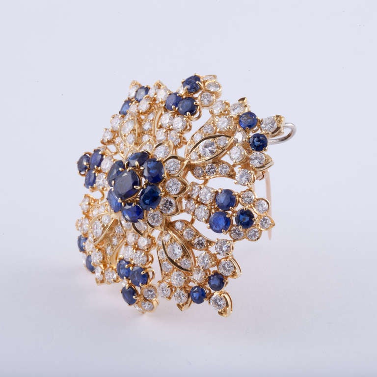 Large brooch composed of 18K yellow gold featuring round blue sapphires that total 11.24 carats and 116 round brilliant-cut diamonds that total 14.24 carats, G-I color and SI1-2 clarity.