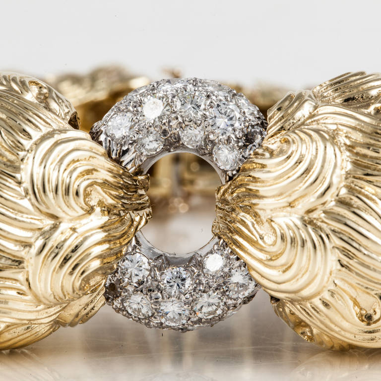 This bracelet by David Webb is 18kt yellow gold with a platinum ring in the center. There are 28 pave-set diamonds that weigh 3.50 carats total weight. The bracelet is slightly flexible and has a clasp and safety chain in the back.