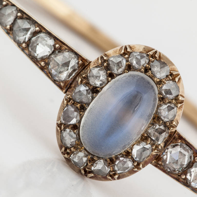 Victorian hinged bangle bracelet in 18K yellow gold featuring an oval moonstone framed by 2.30 carats of rose-cut diamonds.  The bracelet measures 6 1/2 inches.  It is an oval shaped bangle.  Circa 1835-1890.