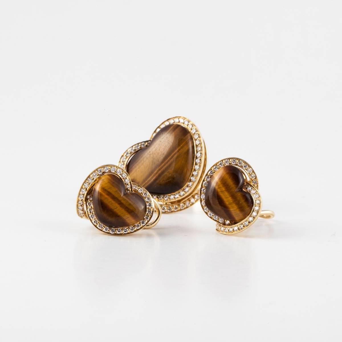 Estate Roberto Coin set of earrings and a ring composed of 18K yellow gold and tiger's eye.   The set features heart-shaped tiger's eye framed by round diamonds.  The earrings are omega backs and measure 5/8 inches across.  The ring's presentation