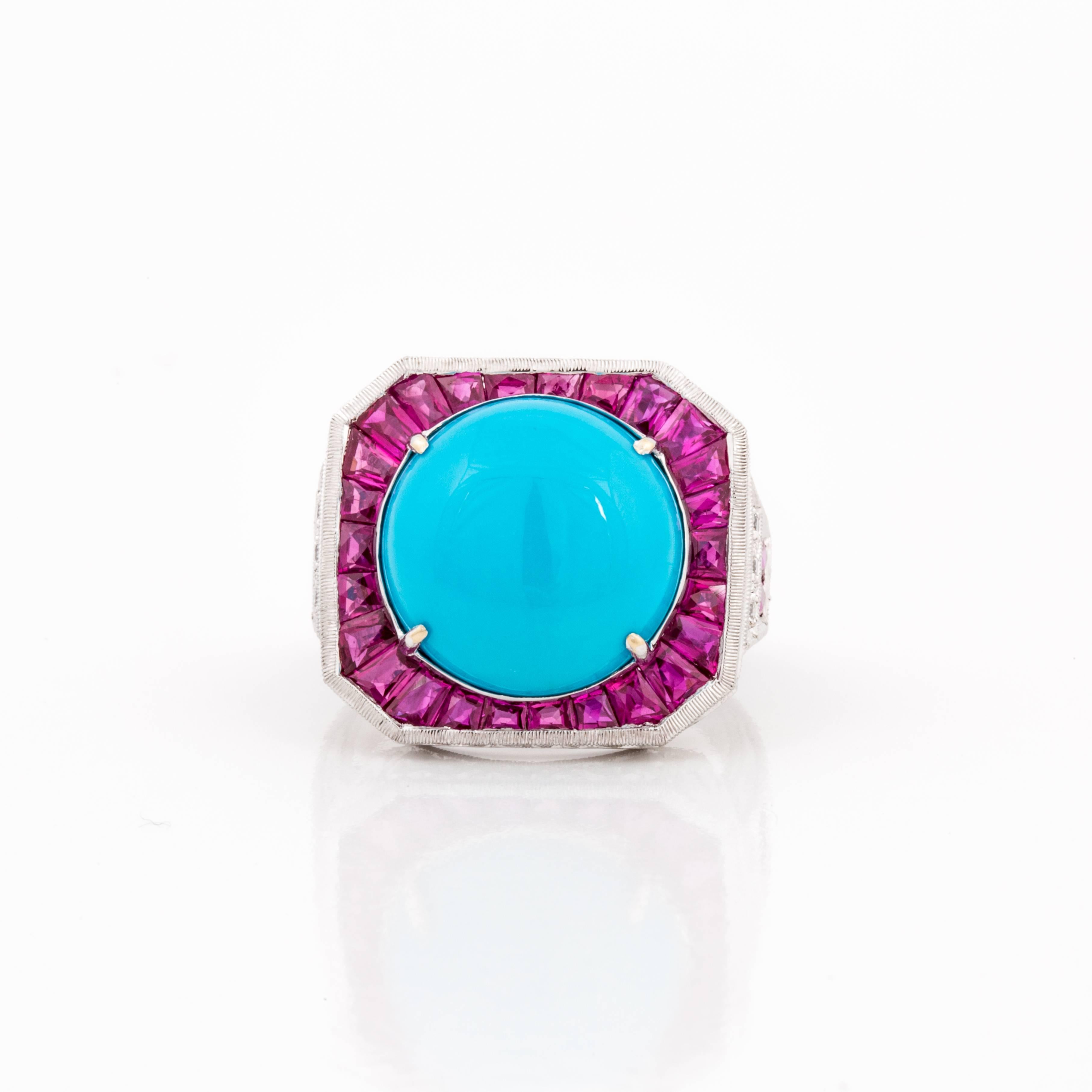 18K white gold ring featuring a round cabochon turquoise stone surrounded by 30 calibré-cut rubies.  The rubies total 3.10 carats.  Additionally there are eight round diamonds that total 0.10 carats, G-H color and VS clarity.  Presentation area is