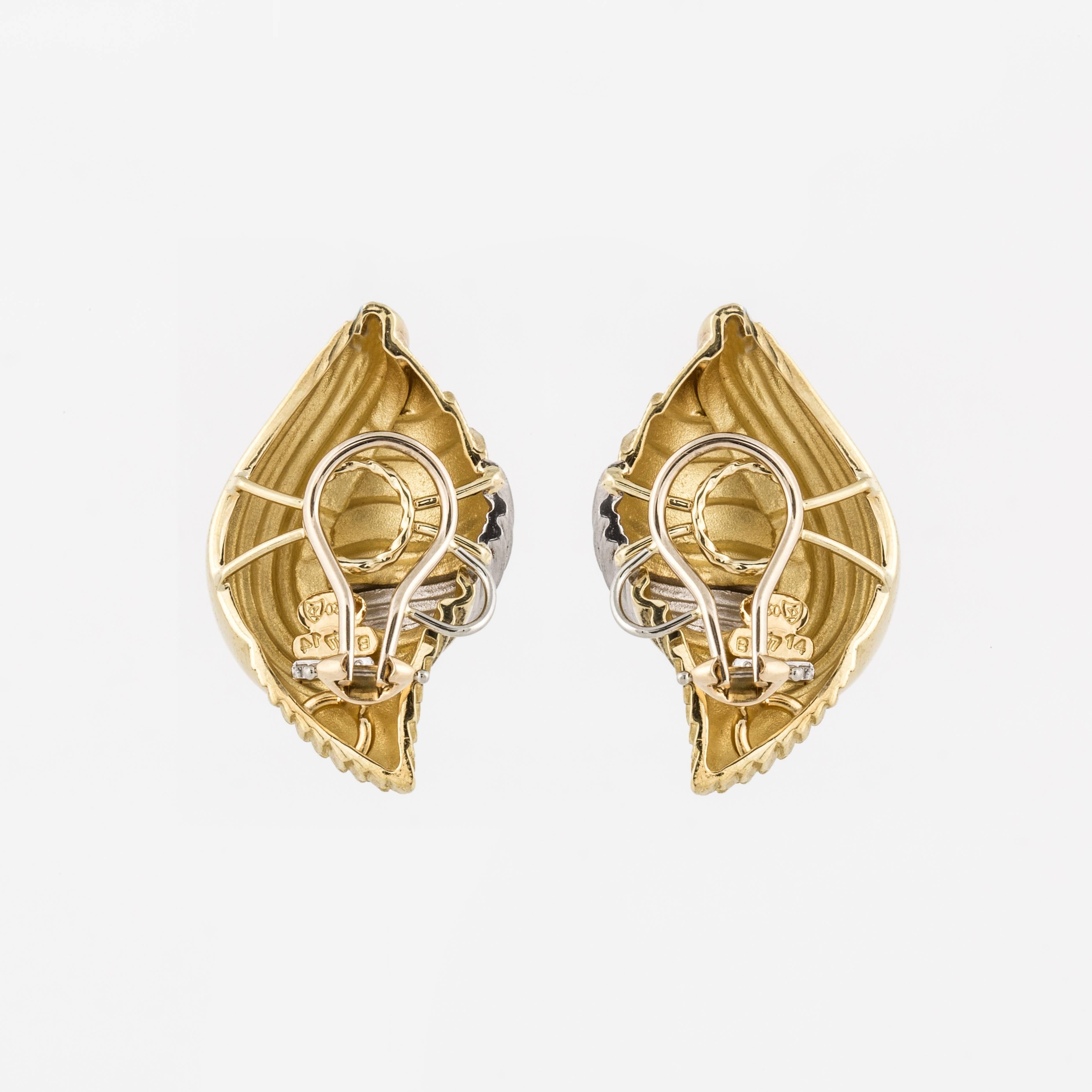 Henry Dunay earrings depicting shells in 18K yellow gold and platinum with a high polish finish in conjunction with a satin finish.  They measure 1 3/8 inches long, 3/4 inches wide and 3/8 inches deep.  They have clip backs.  The earrings are marked