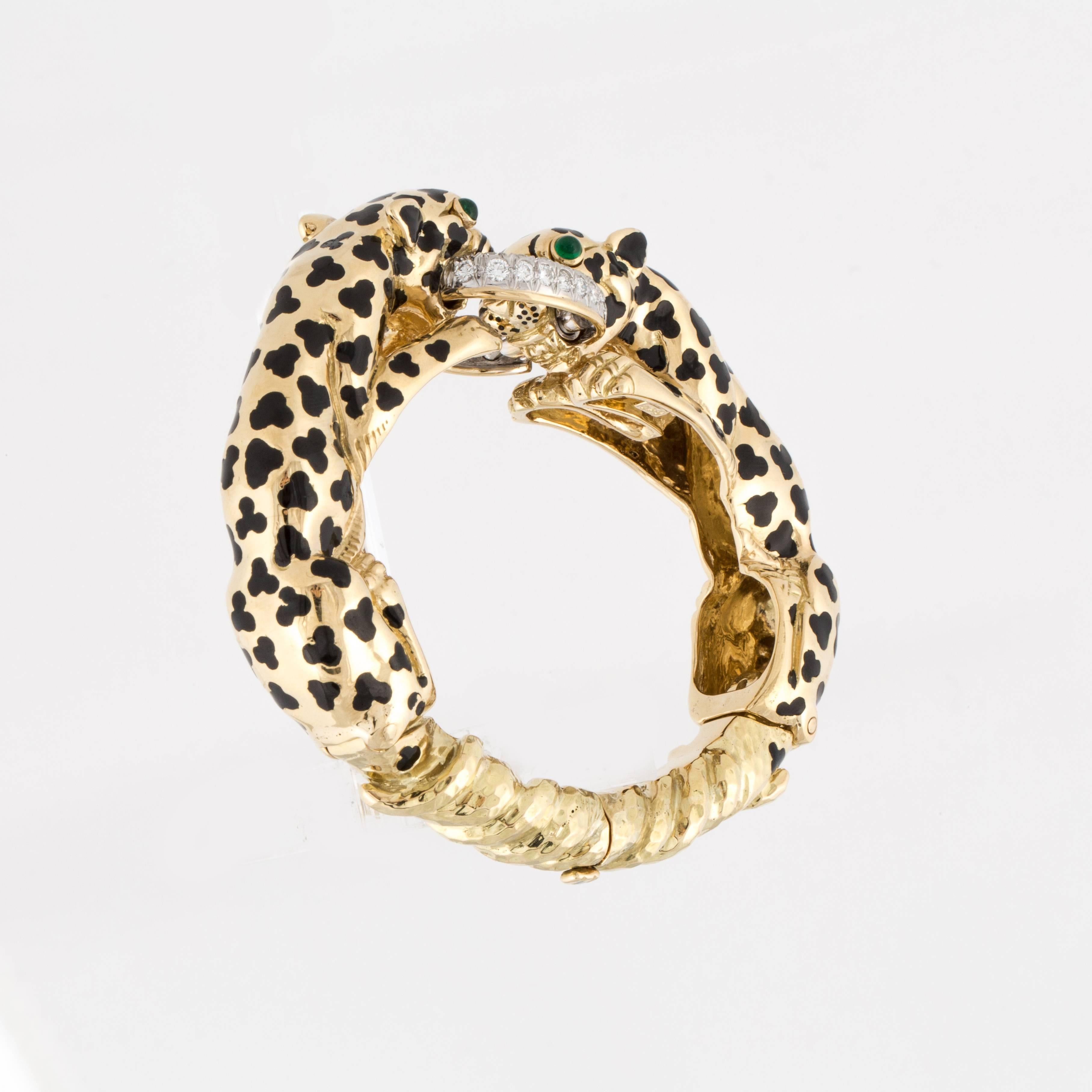 David Webb double leopard bangle bracelet in 18K yellow gold with black enamel spots and emerald eyes.  The leopards are biting a pavé diamond ring with 52 round brilliant-cut diamonds that total 4.15 carats, F-G color and VVS1-VS1 clarity.  The