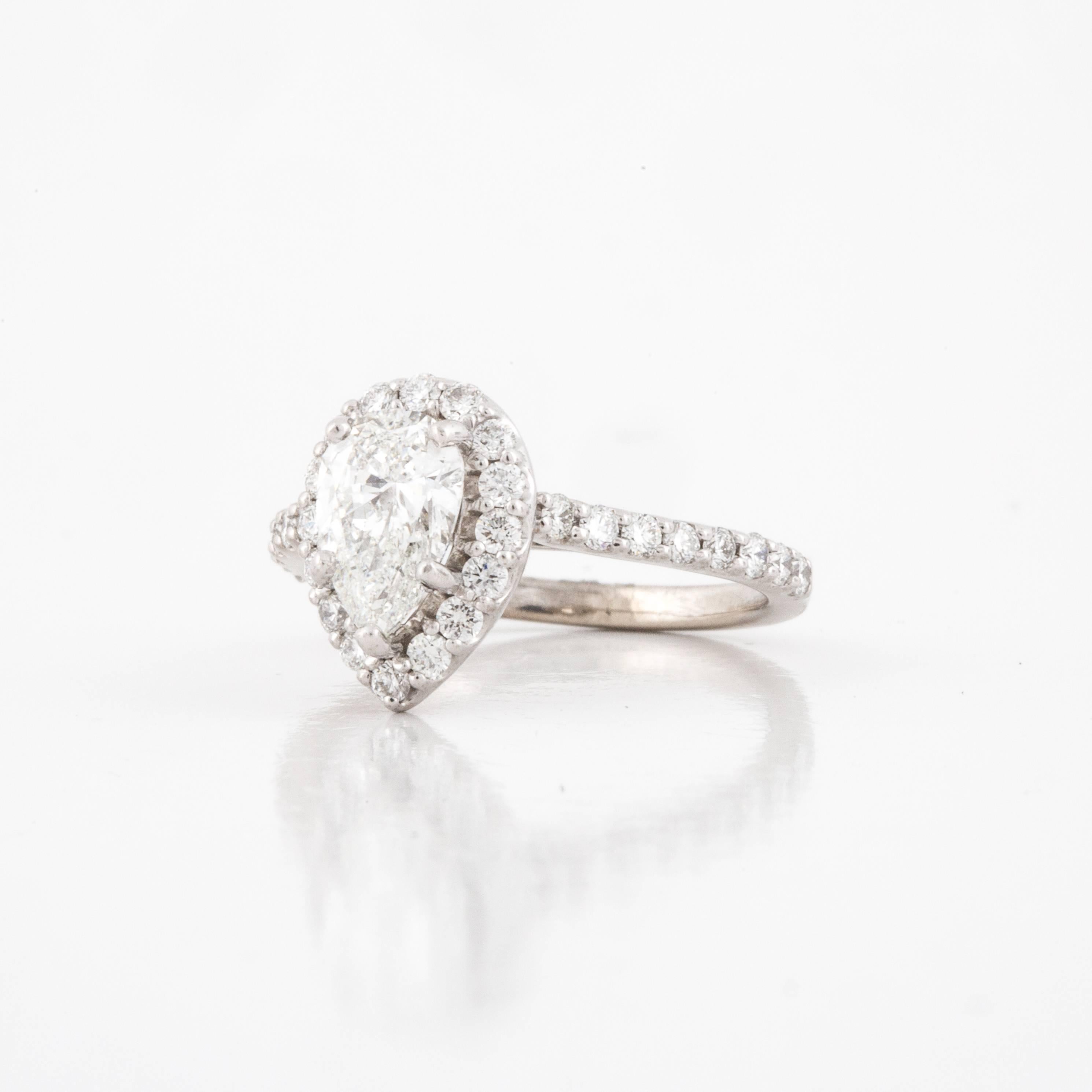 This halo style engagement ring by Ritani features a pear shaped diamond in 14K white gold.  The pear shaped diamond is 0.82 carats, F-G color and SI1-2 clarity.  It is accented by thirty-two (32) round diamonds that total 0.50 carats, G-H color and