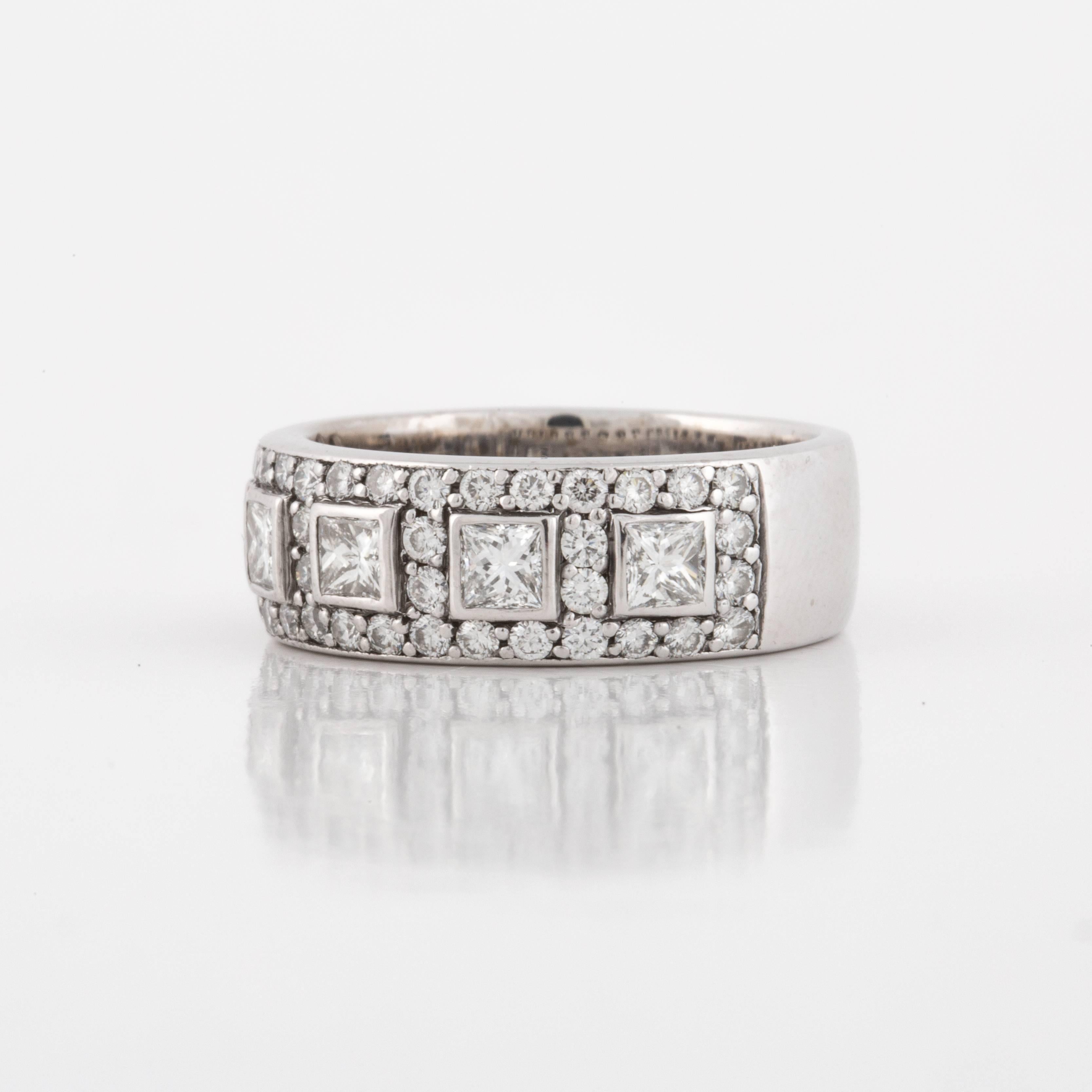 White gold band composed of 18K white gold.  The top is set with five (5) princess cut diamonds, bezel set, that total .65 carats.  Additionally there are forty-four (44) round diamonds which total 0.90 carats.  The total carat weight of the ring is