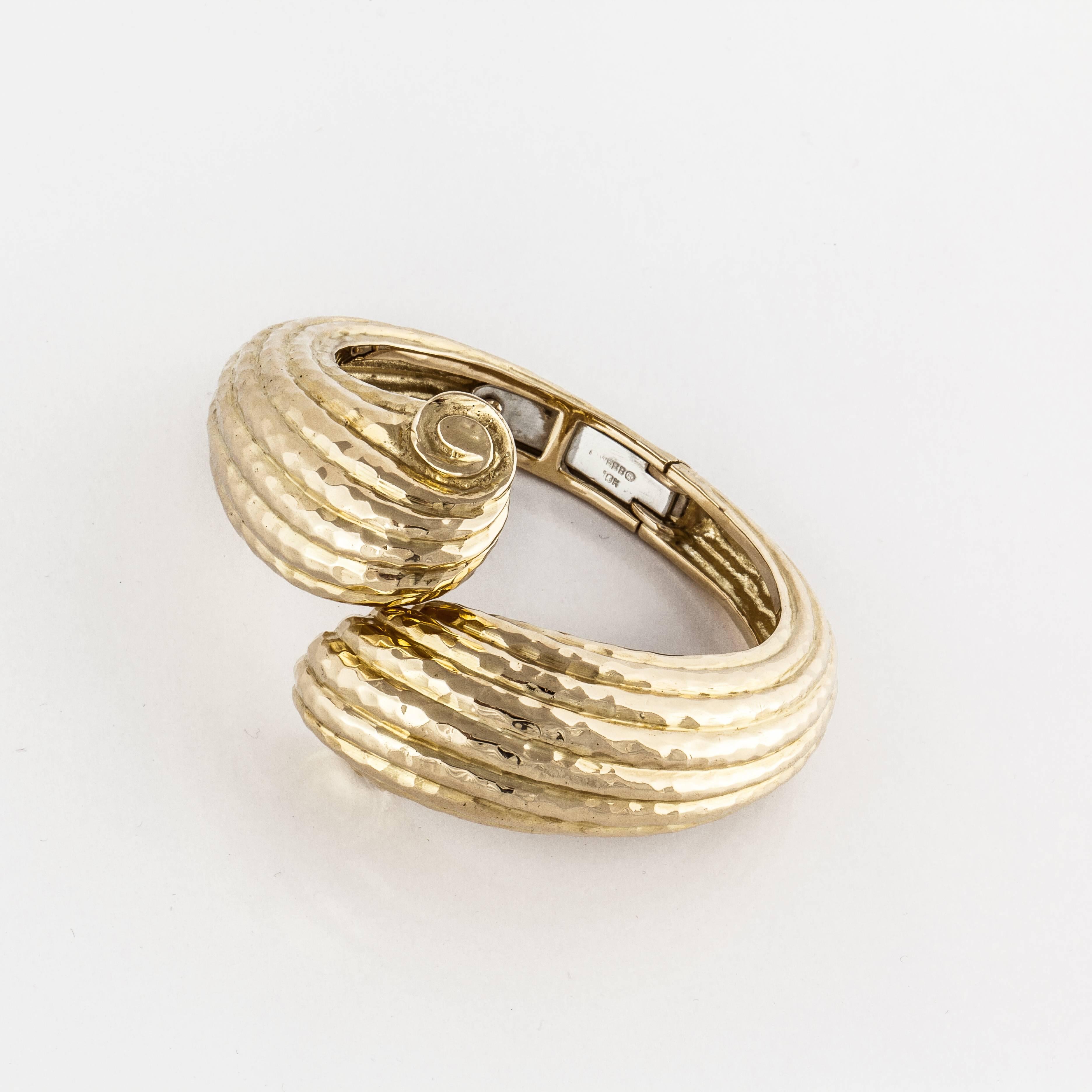 David Webb crossover styled bangle bracelet in 18K hammered yellow gold, hinged at the bottom.  Marked on the inside 