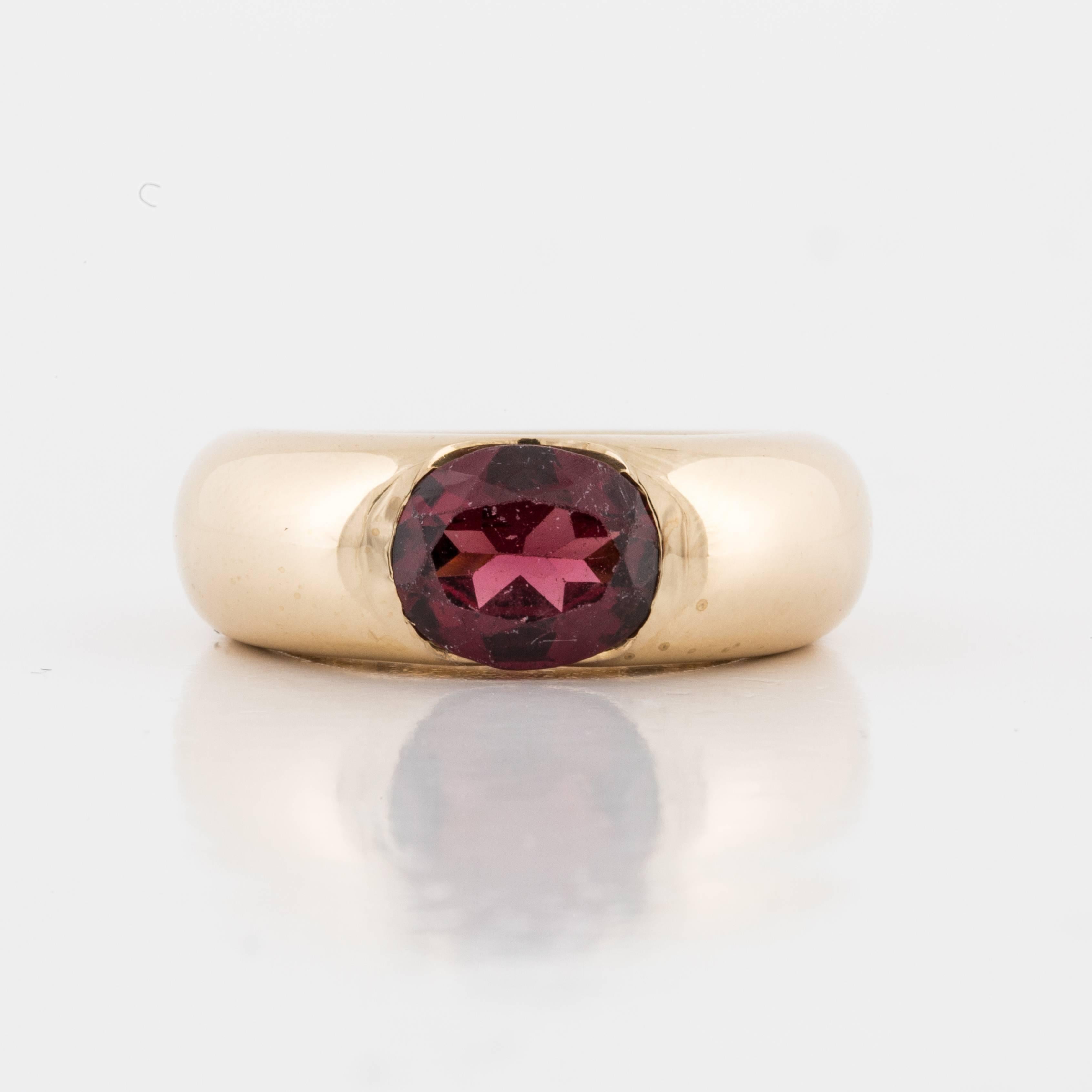 Cartier ring in 18K yellow gold featuring an oval faceted garnet.  The ring is marked on the inside 