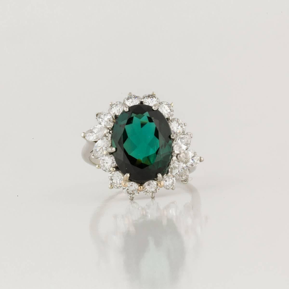 Classic cocktail ring featuring a green tourmaline framed by diamonds and set in platinum (stamped PT950). The oval faceted tourmaline weighs 4.50 carats.  It is accented by ten (10) round diamonds totaling 1.25 carats and six (6) marquise diamonds