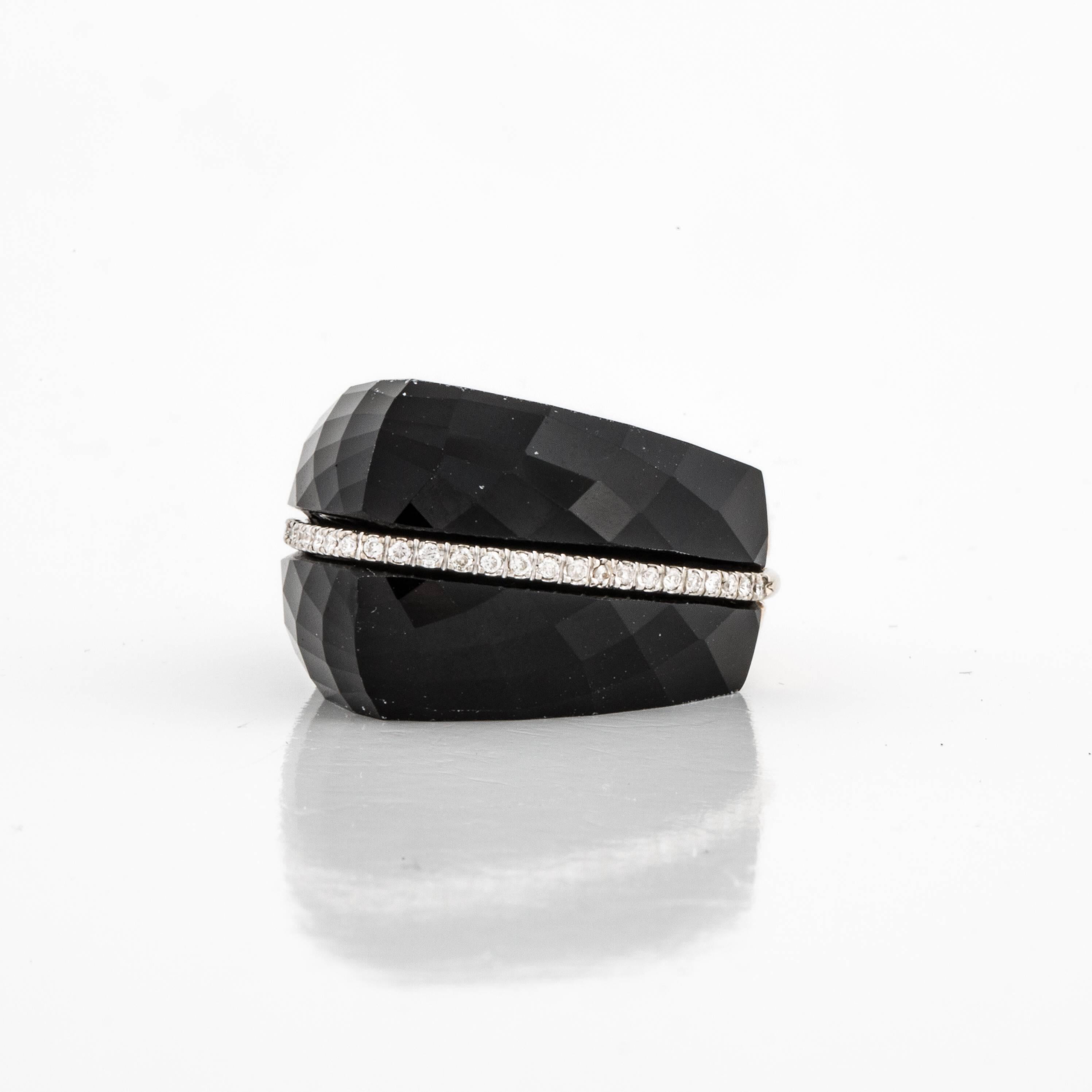 This modern ring by Mazza features faceted onyx with a row of diamonds across the top.  There is a total of 0.17 carats of diamonds.  The ring is constructed in yellow gold and marked on the inside 