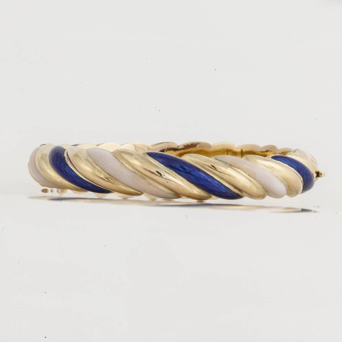 Tiffany & Co. bangle bracelet composed of 18K yellow gold with a rope pattern in alternating blue and white enamel.  The bracelet is marked 