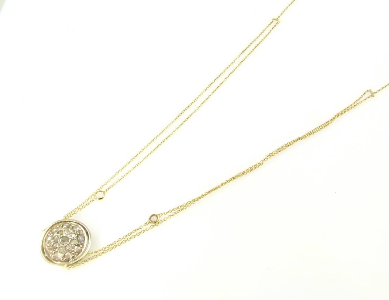 An 18 karat yellow gold and rose cut diamond pendant necklace, Signed Renee Lewis 18KT.  The center disc form pendant is pave set with 18 rose cut diamonds, and 2 collet set diamonds are set in the double chain necklace with toggle closure.  The 20