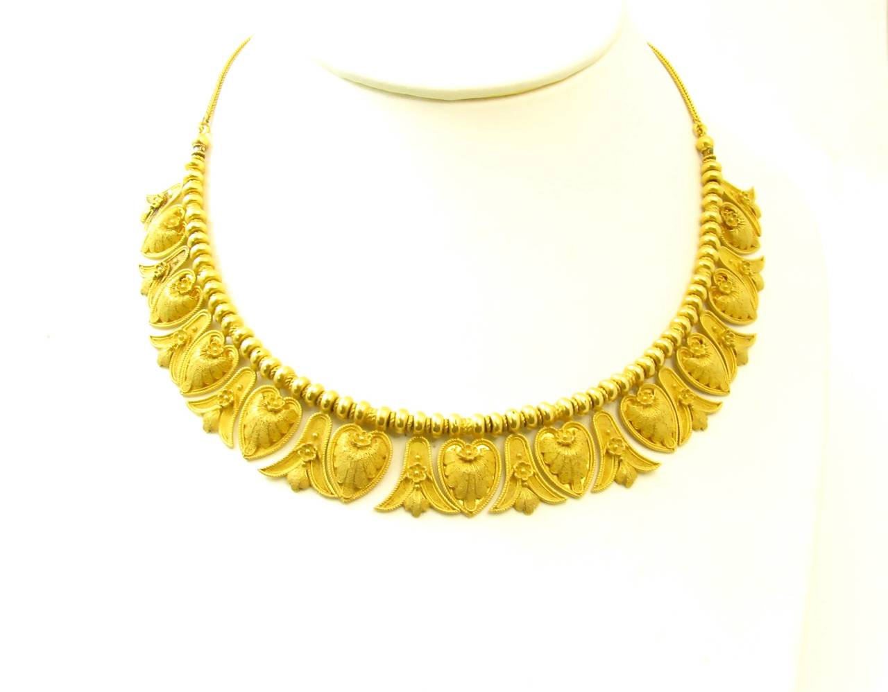 An antique Italian 18 karat yellow gold Etruscan style necklace, Circa 1870s.  The antique fitted box is signed Achille Squadrilli, Piazza Vittoria Napoli.  The necklace is designed as alternating pendants of granulated bellflower and anthemion
